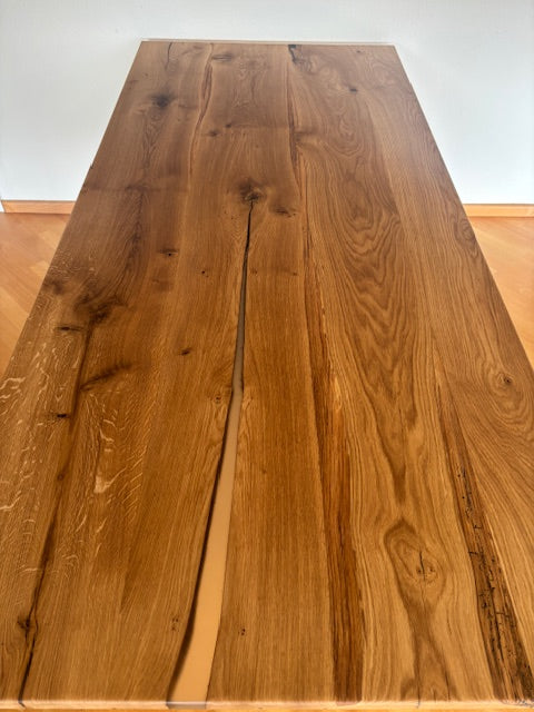 Esstisch aus Eiche mit Kreuzfuß von Wildwuchs-Möbel, zeigt natürliche Holzmaserung und elegantes Design.