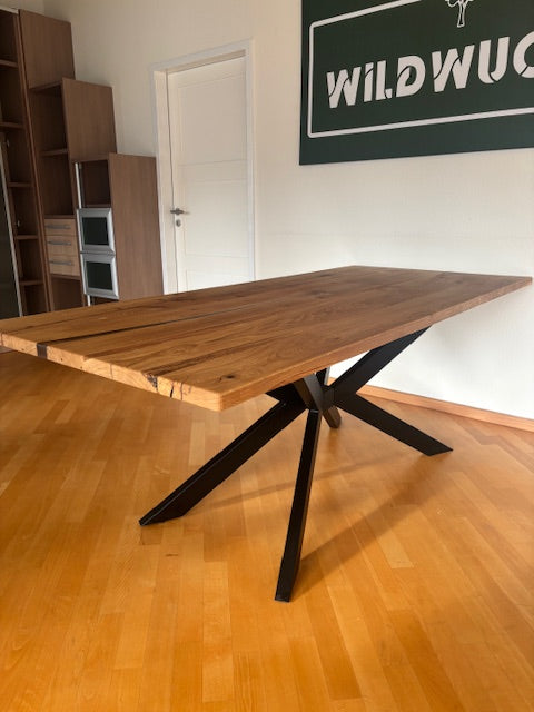 Esstisch aus Eiche mit Kreuzfuß von Wildwuchs-Möbel, Holzoberfläche und natürlicher Maserung sichtbar.